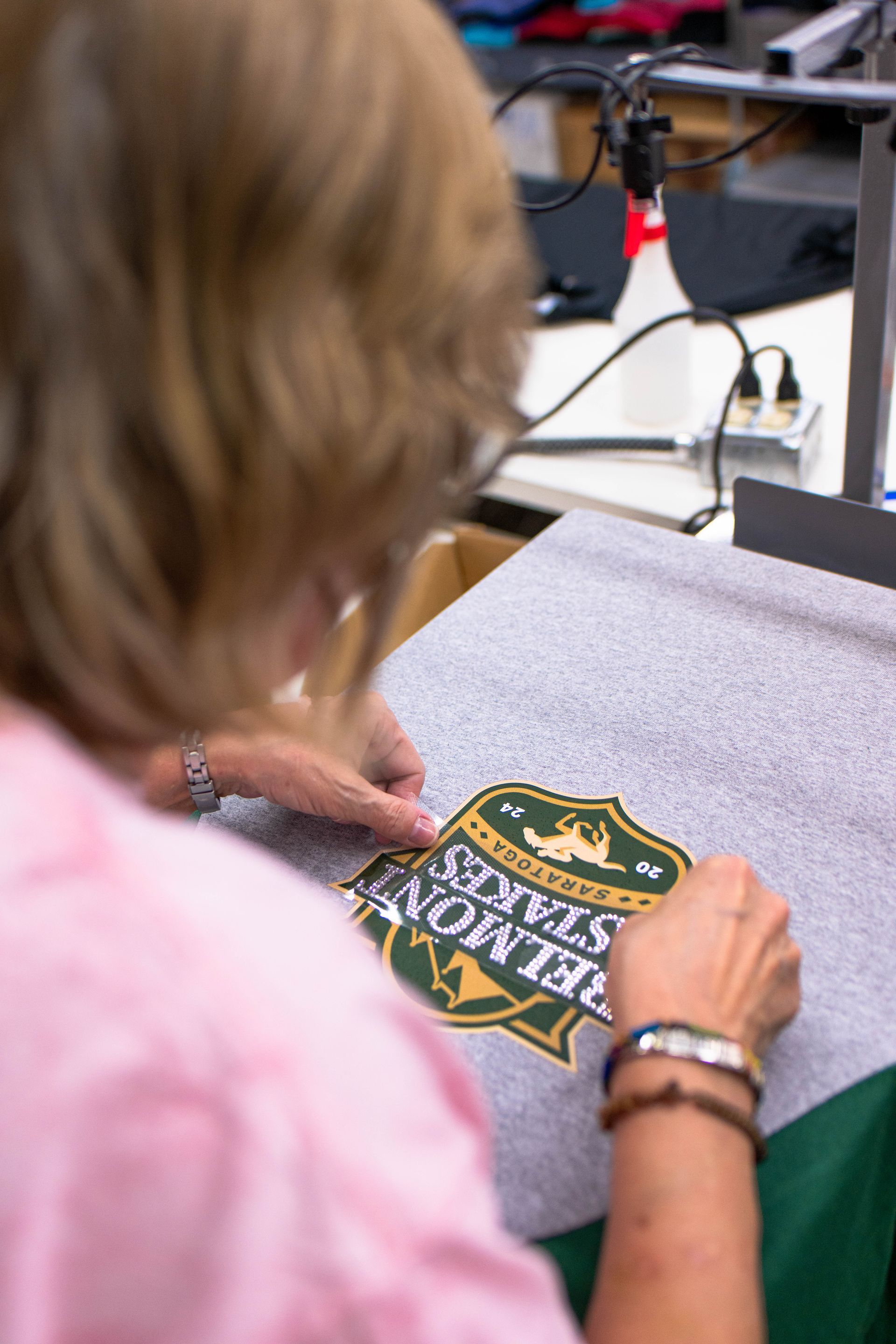 A woman is working on a shirt that says belmont state
