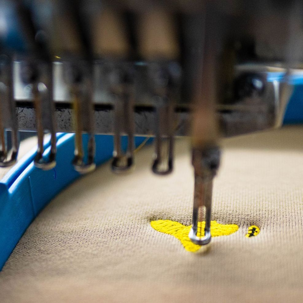 A close up of a machine embroidery a bee on a piece of fabric.