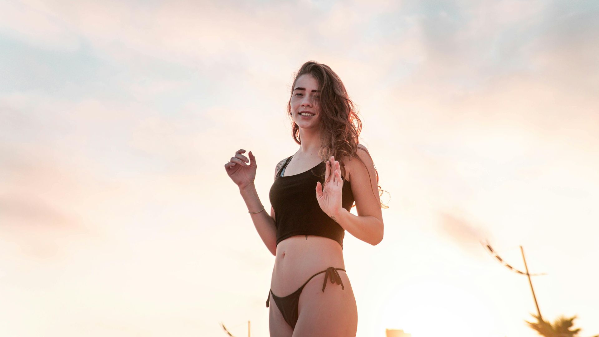 Woman in a black bikini standing outdoors at sunset in myrtle beach sc with fresh waxed skin