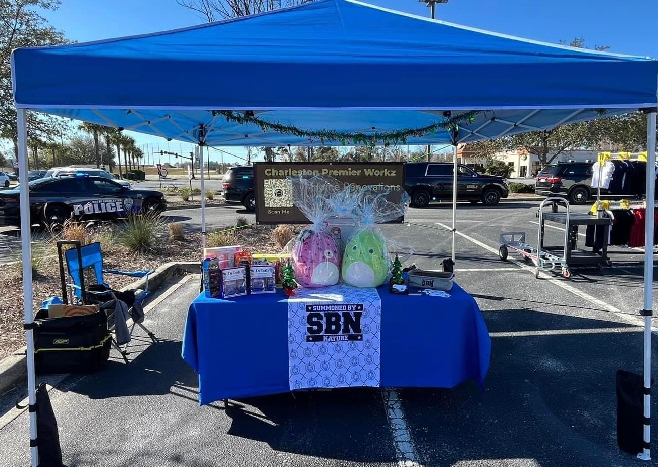 A blue tent with a table underneath it in a parking lot.