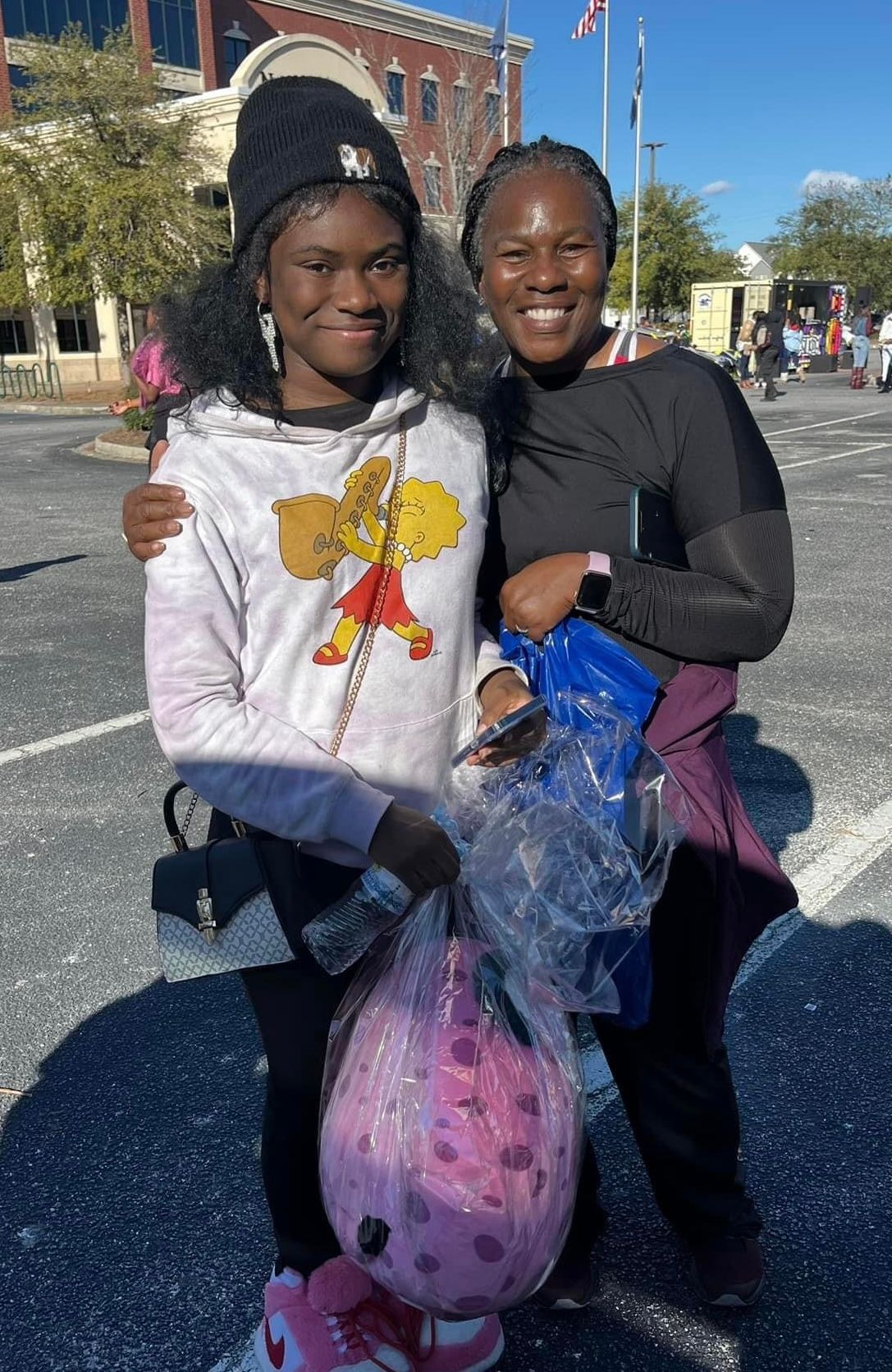 Two women are standing next to each other in a parking lot.