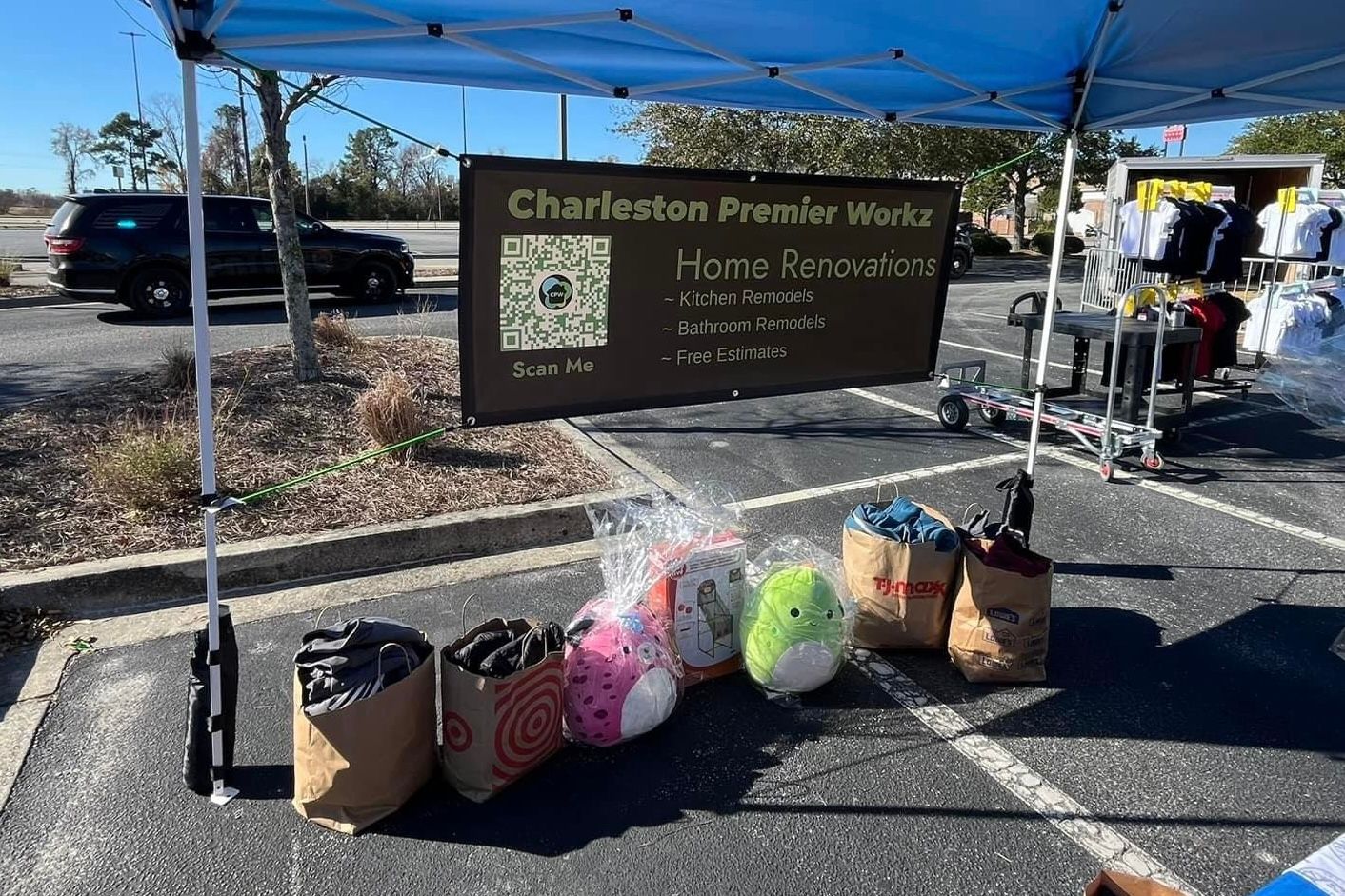 A blue tent is sitting in a parking lot next to a sign.
