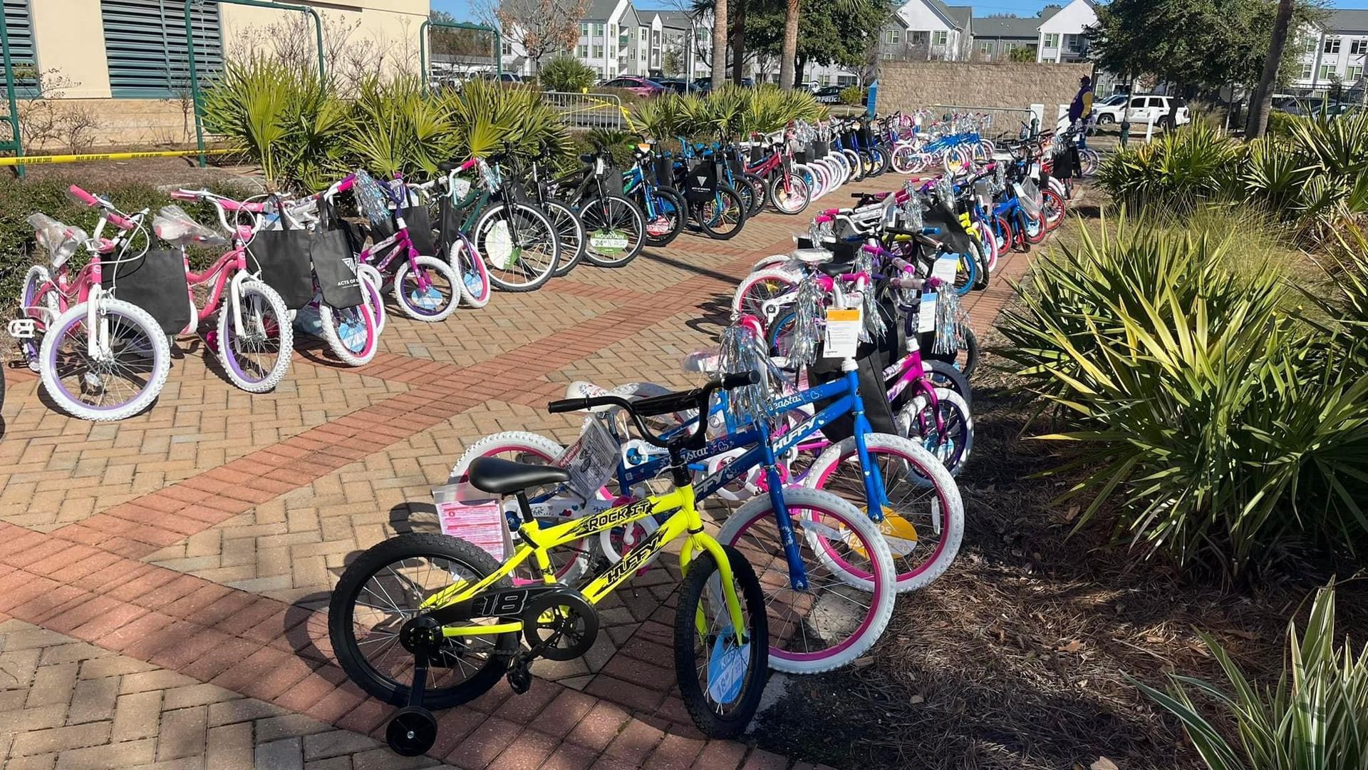 A row of bicycles are parked on a brick sidewalk.