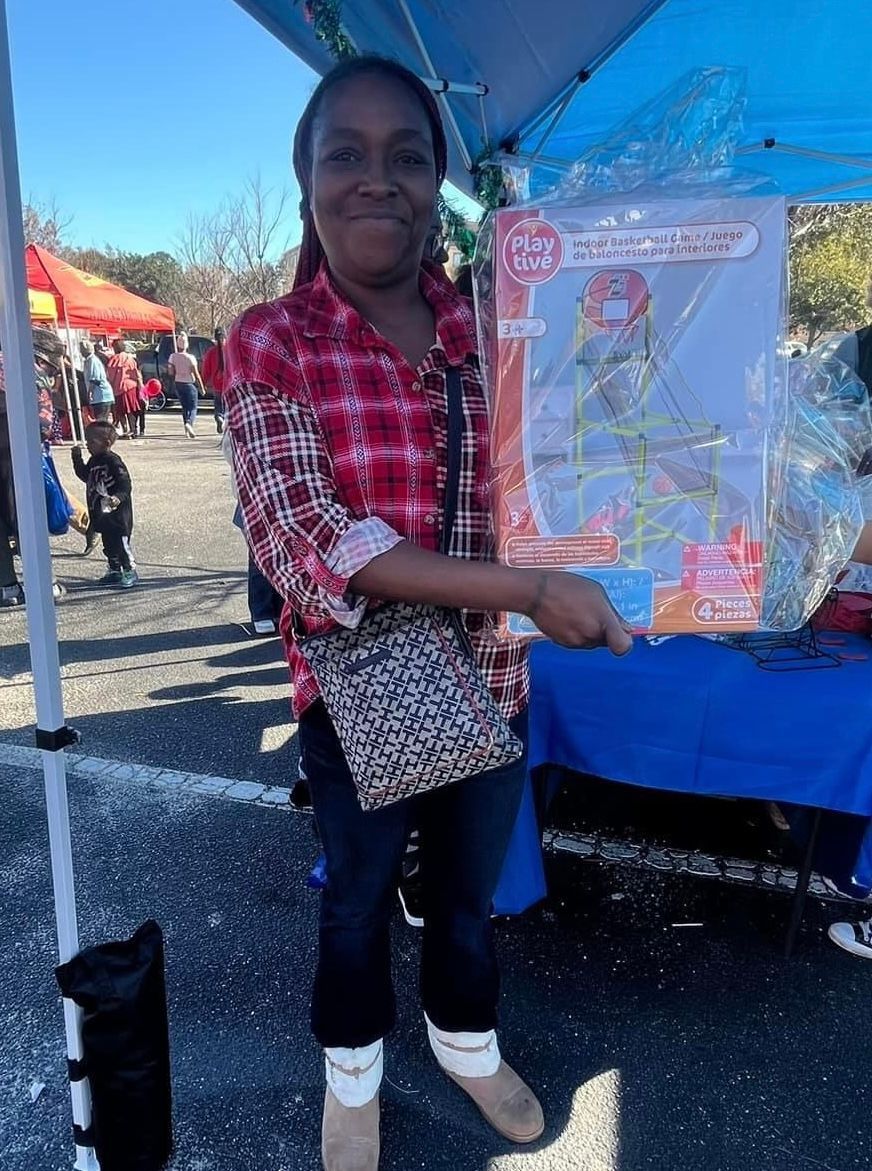 A woman in a plaid shirt is standing in front of a tent holding a toy.