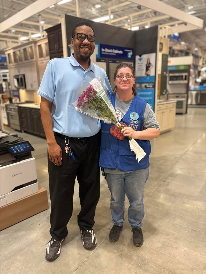 A man and a woman are standing next to each other in a store holding flowers.