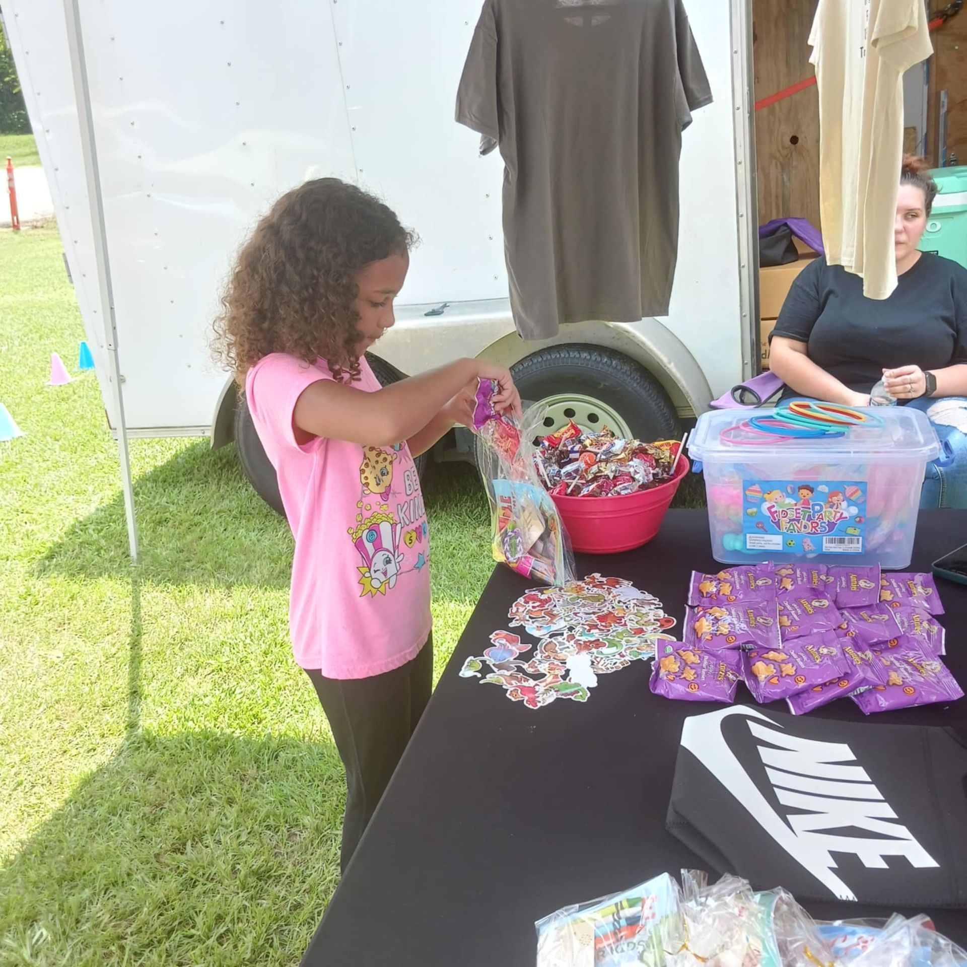 A girl in a pink shirt is standing in front of a table