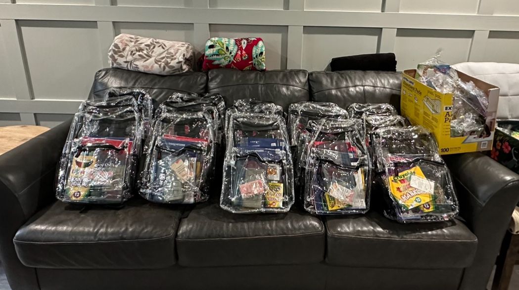 A couch with a bunch of backpacks on it.