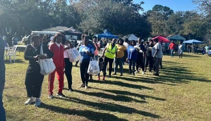 A group of people are standing in a line in a grassy field.