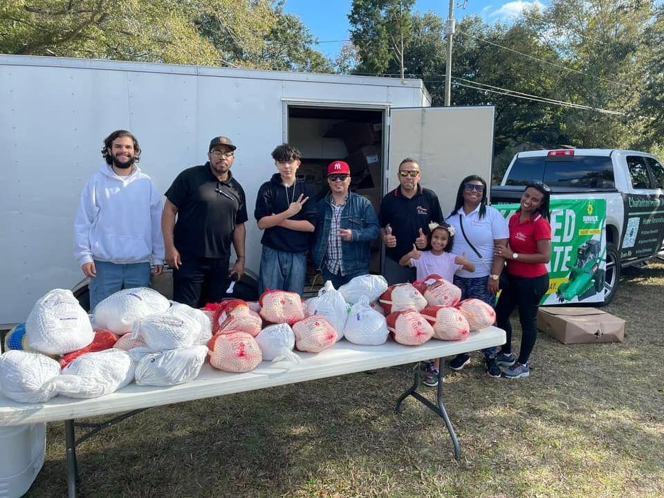 A group of people are standing around a table filled with turkeys.