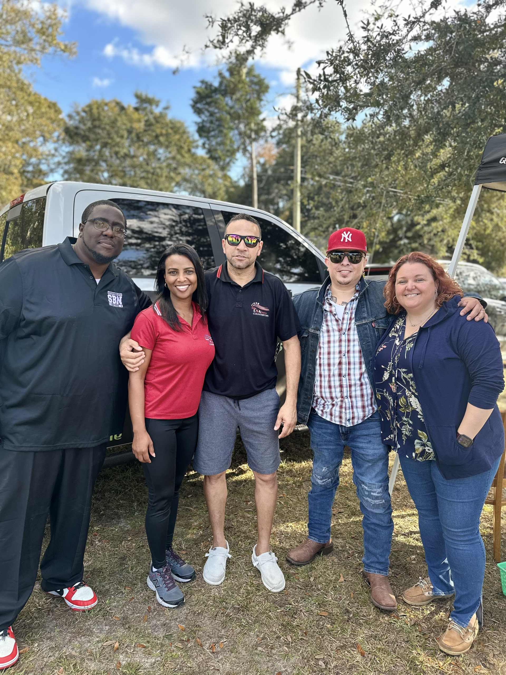 A group of people are posing for a picture in front of a truck.