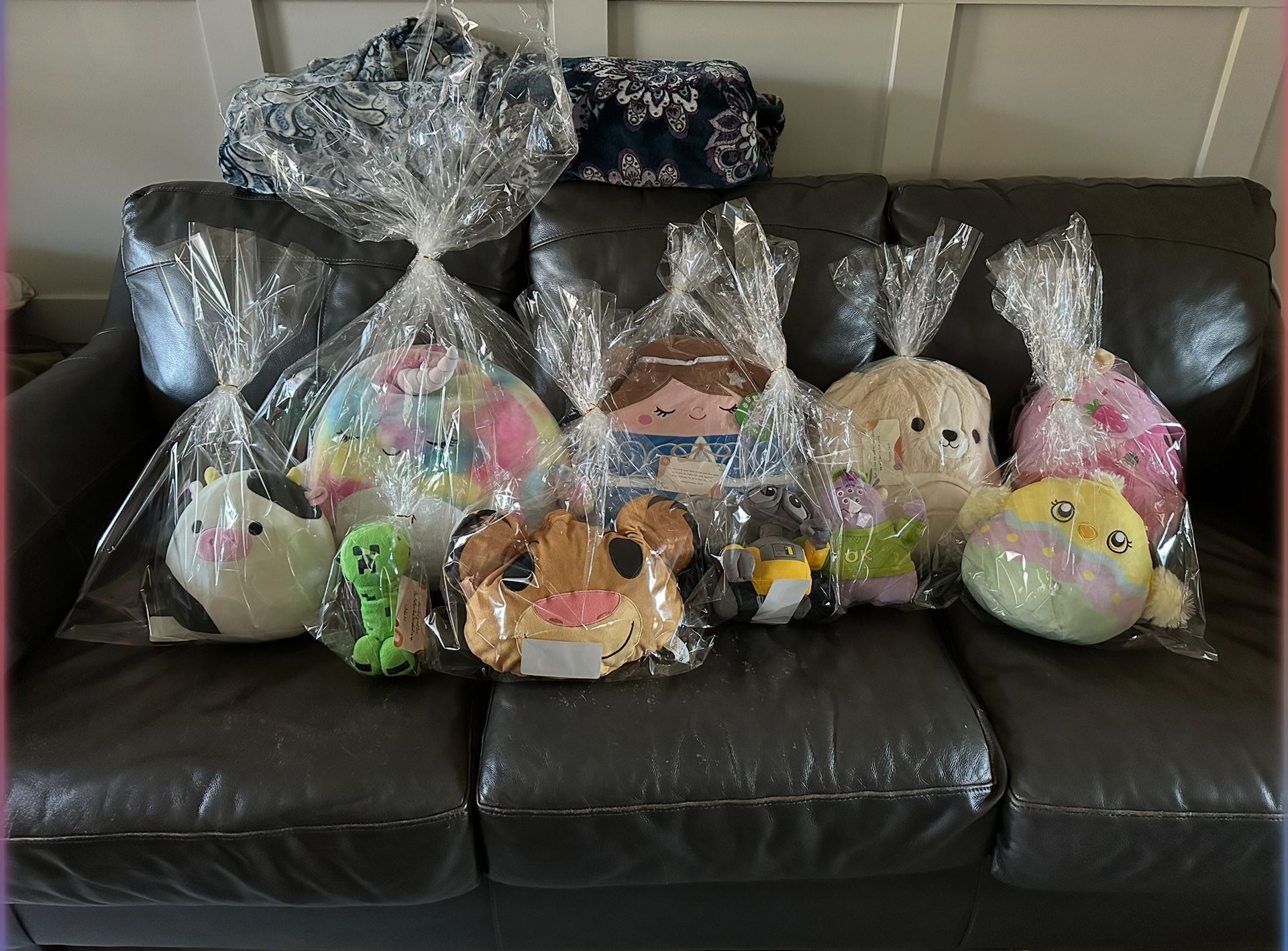 A couch with a bunch of stuffed animals wrapped in plastic