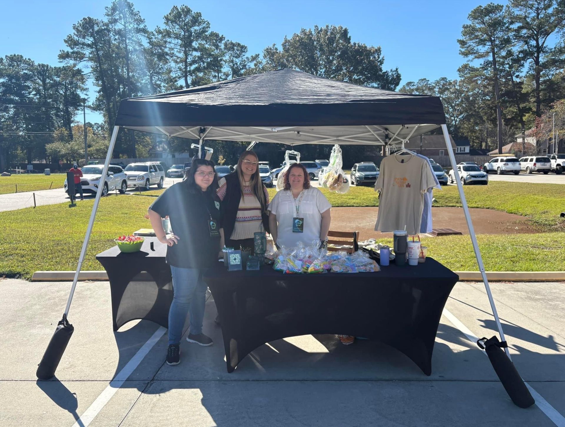 A group of people standing under a tent in a parking lot