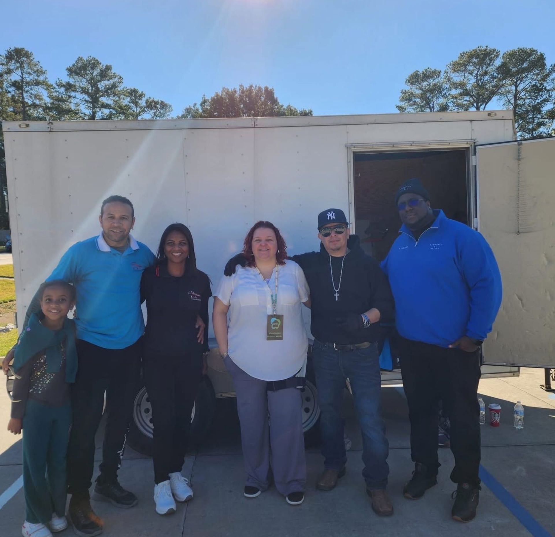 A group of people posing for a picture in front of a trailer