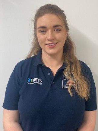 A woman is wearing a blue polo shirt and smiling.