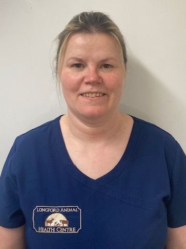 A woman in a blue scrub top is smiling for the camera.