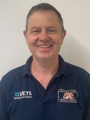 A man wearing a blue polo shirt is smiling for the camera.