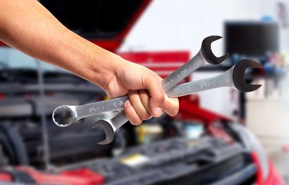 A Person Is Holding Three Wrenches In Front Of A Car With The Hood Open — Warrmech Mechanical In Tweed Heads South, NSW