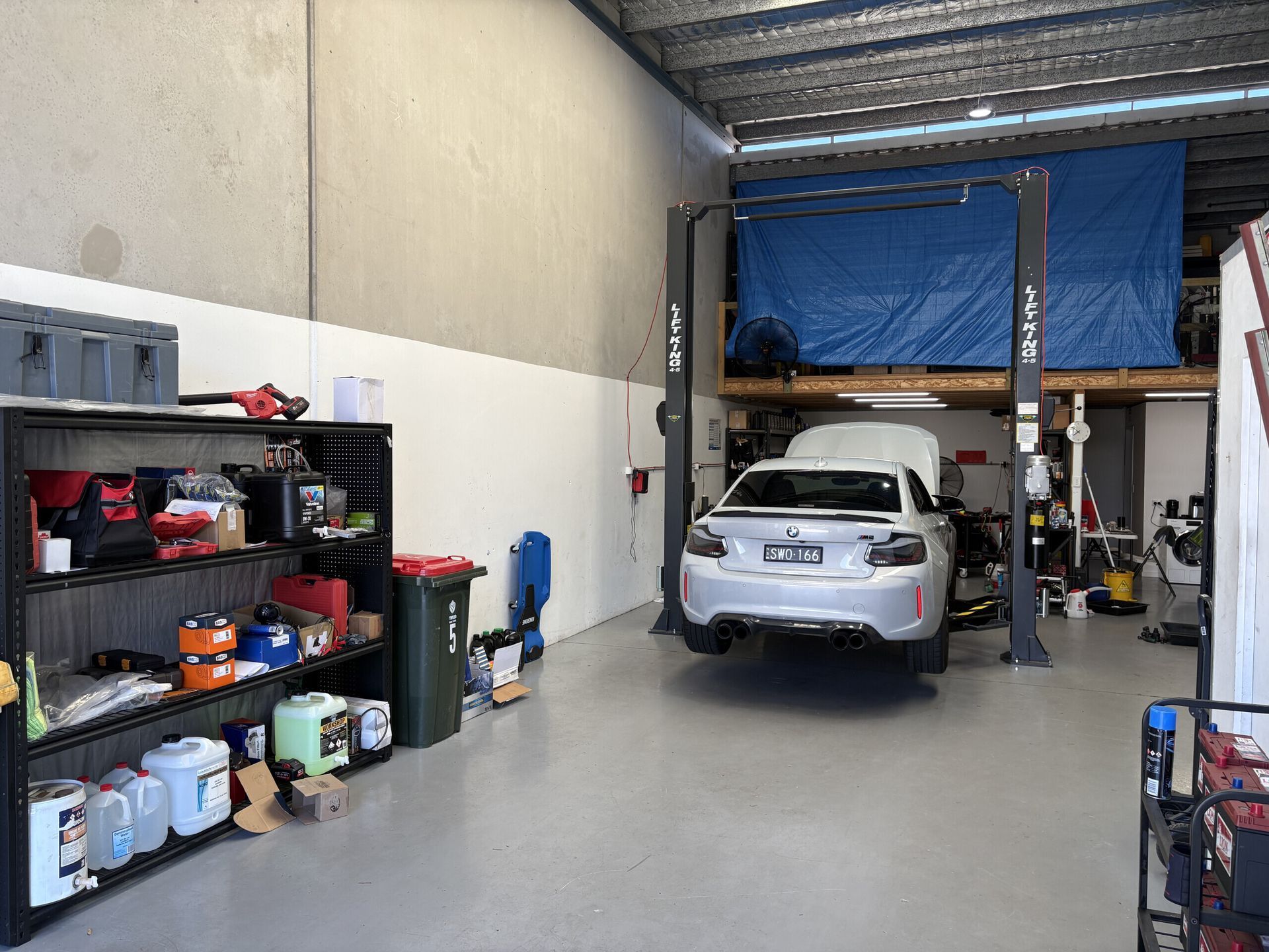 A Man Is Working On The Battery Of A Car — Warrmech Mechanical In Tweed Heads South, NSW
