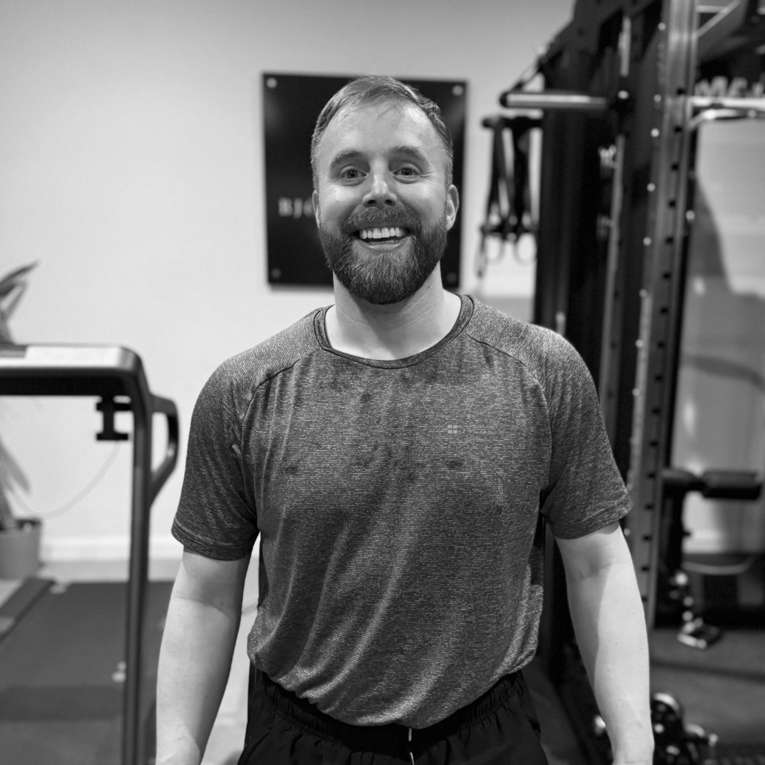 Man smiling in a gym setting, wearing a gray shirt.