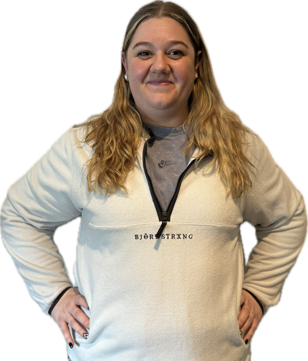 Woman in a cream-colored fleece sweatshirt with hands on hips. She is smiling.