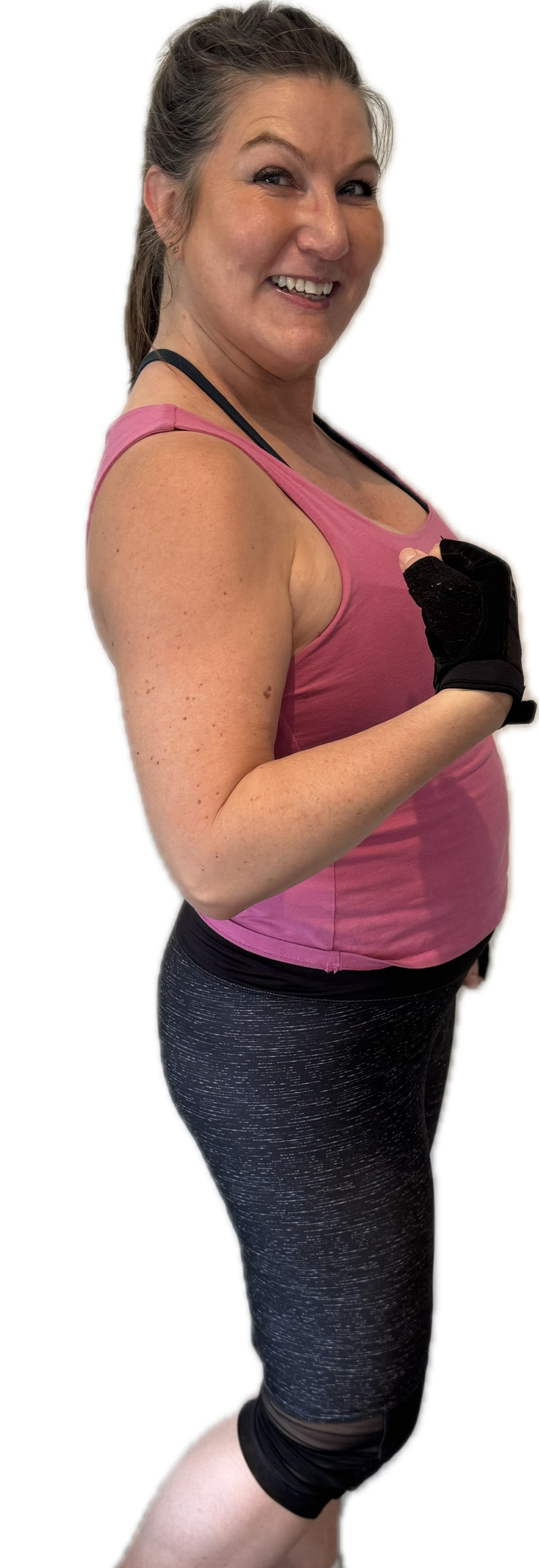 Woman in pink tank top curls her arm, wearing black fitness gloves and grey speckled leggings.