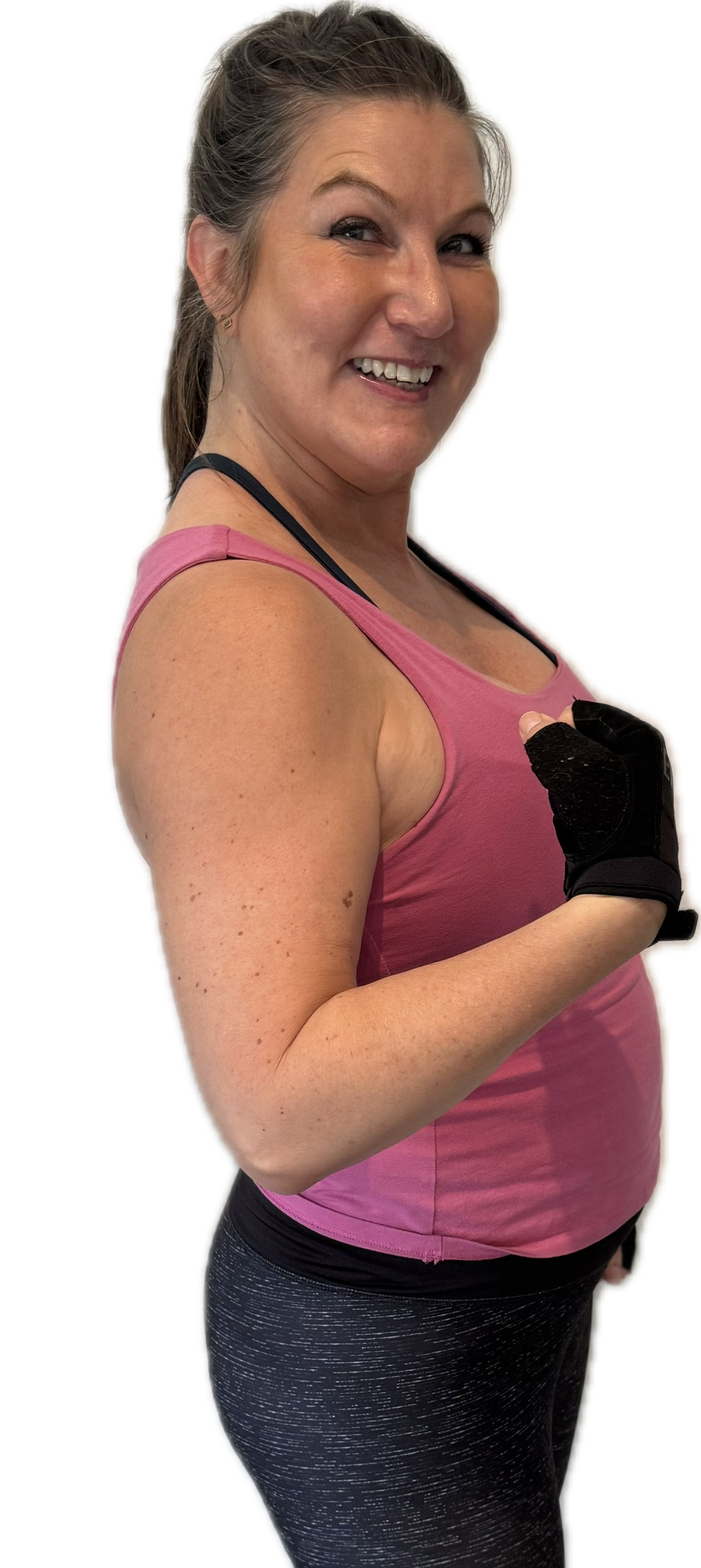 Woman in pink tank top curls her arm, wearing black fitness gloves and grey speckled leggings.