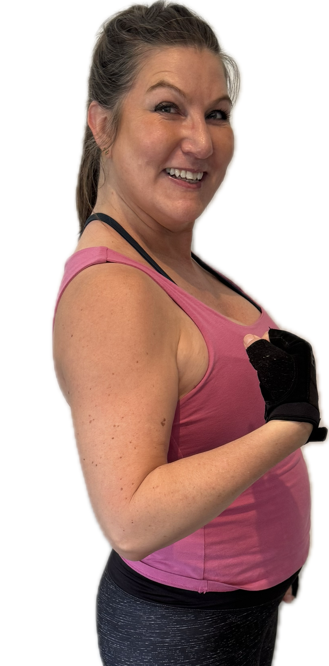 Woman in pink tank top and black gloves, smiling and flexing arm.