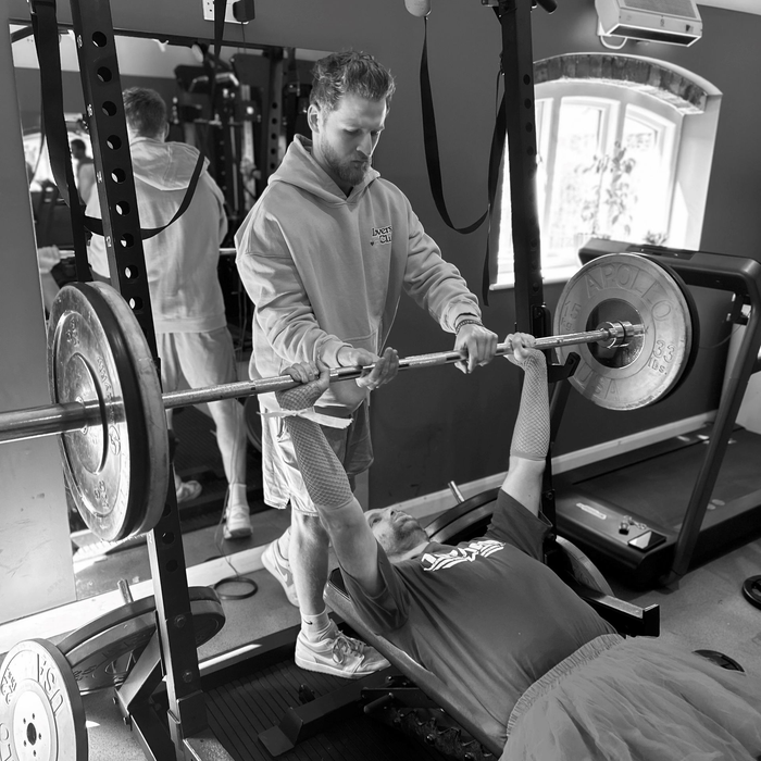 Group of people posing outdoors in front of a thatched-roof building.