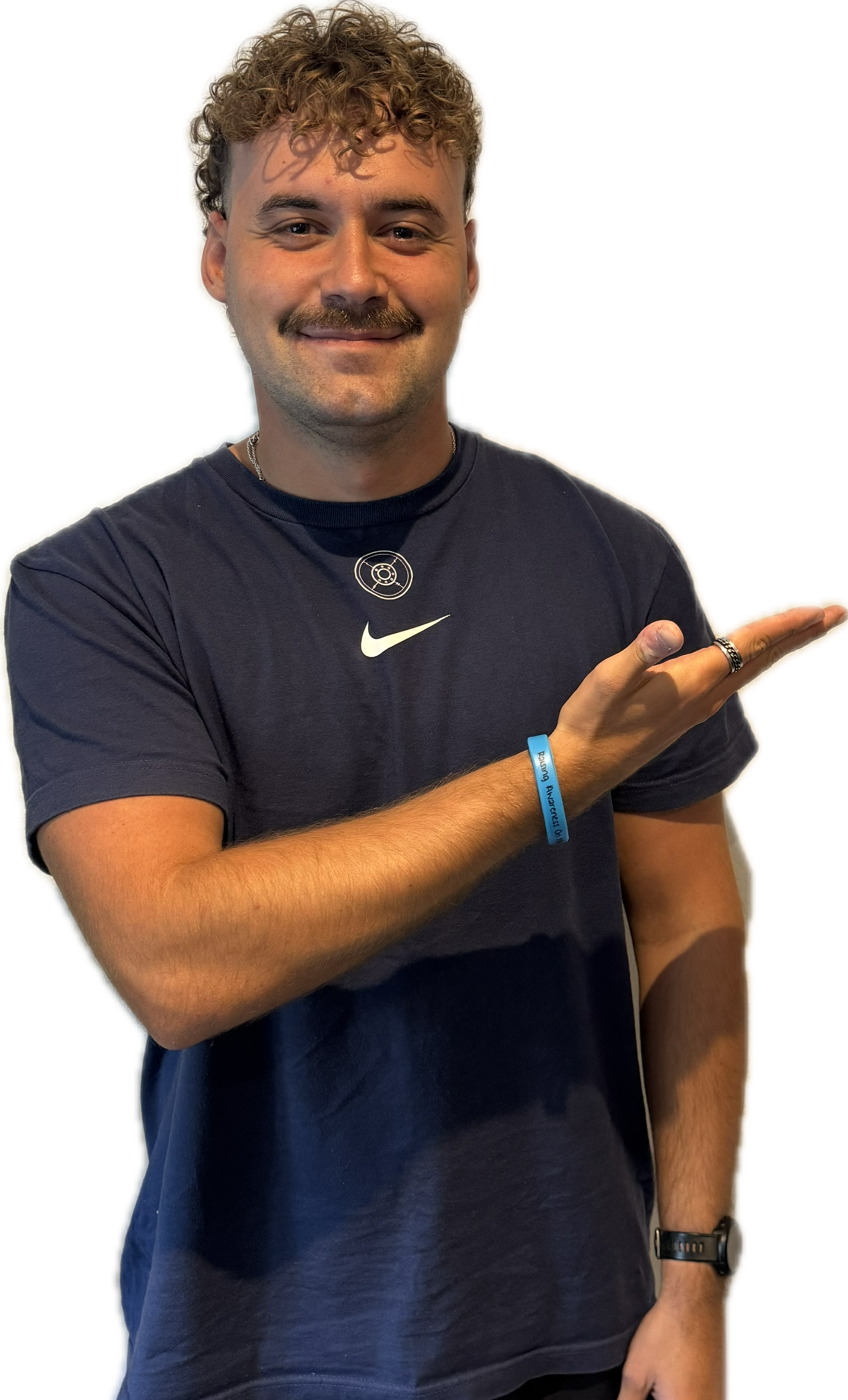 Man in navy shirt pointing to the right, smiling. Curly brown hair, mustache, and a blue wristband.