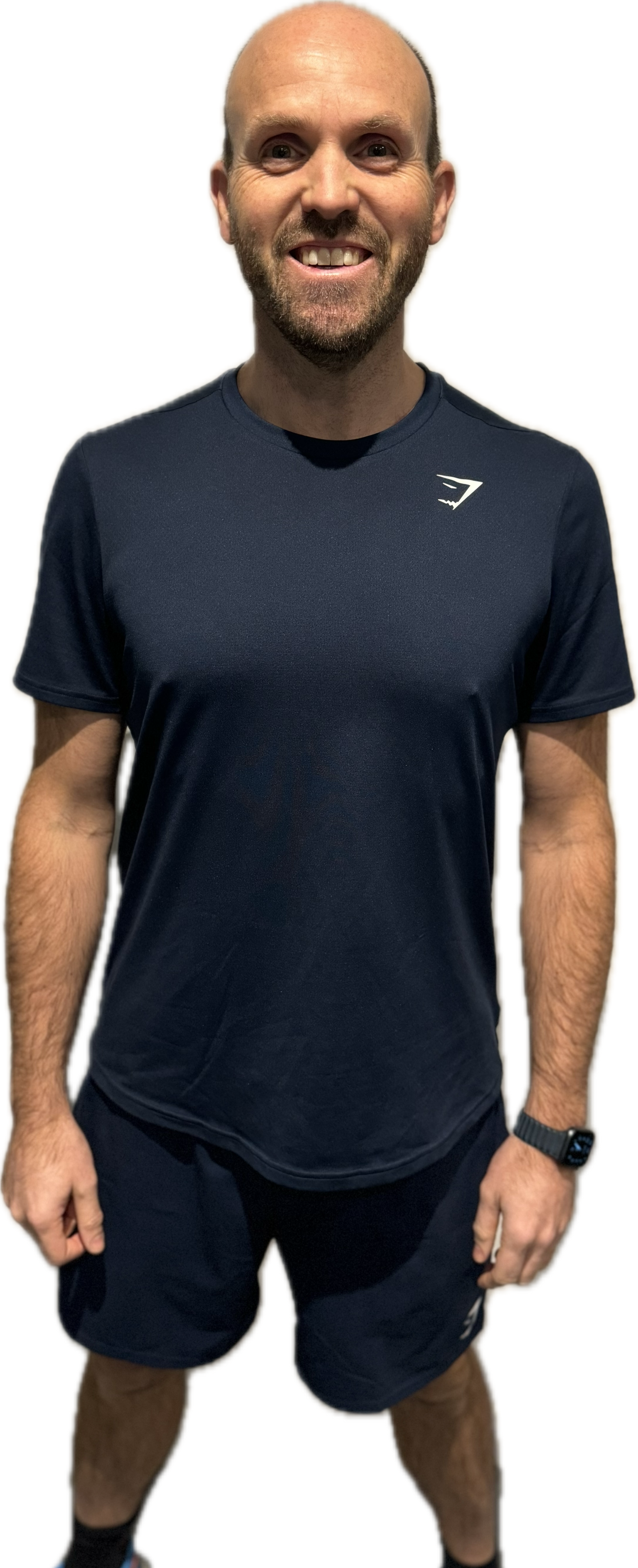 Woman with curly hair, smiling, wearing black workout clothes, pointing.