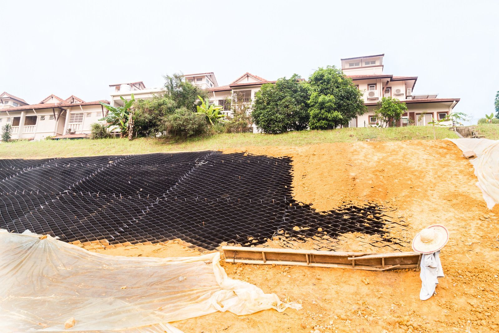 White bathtub with tiled walls in a bathroom, light brown floor, faucet on the side.