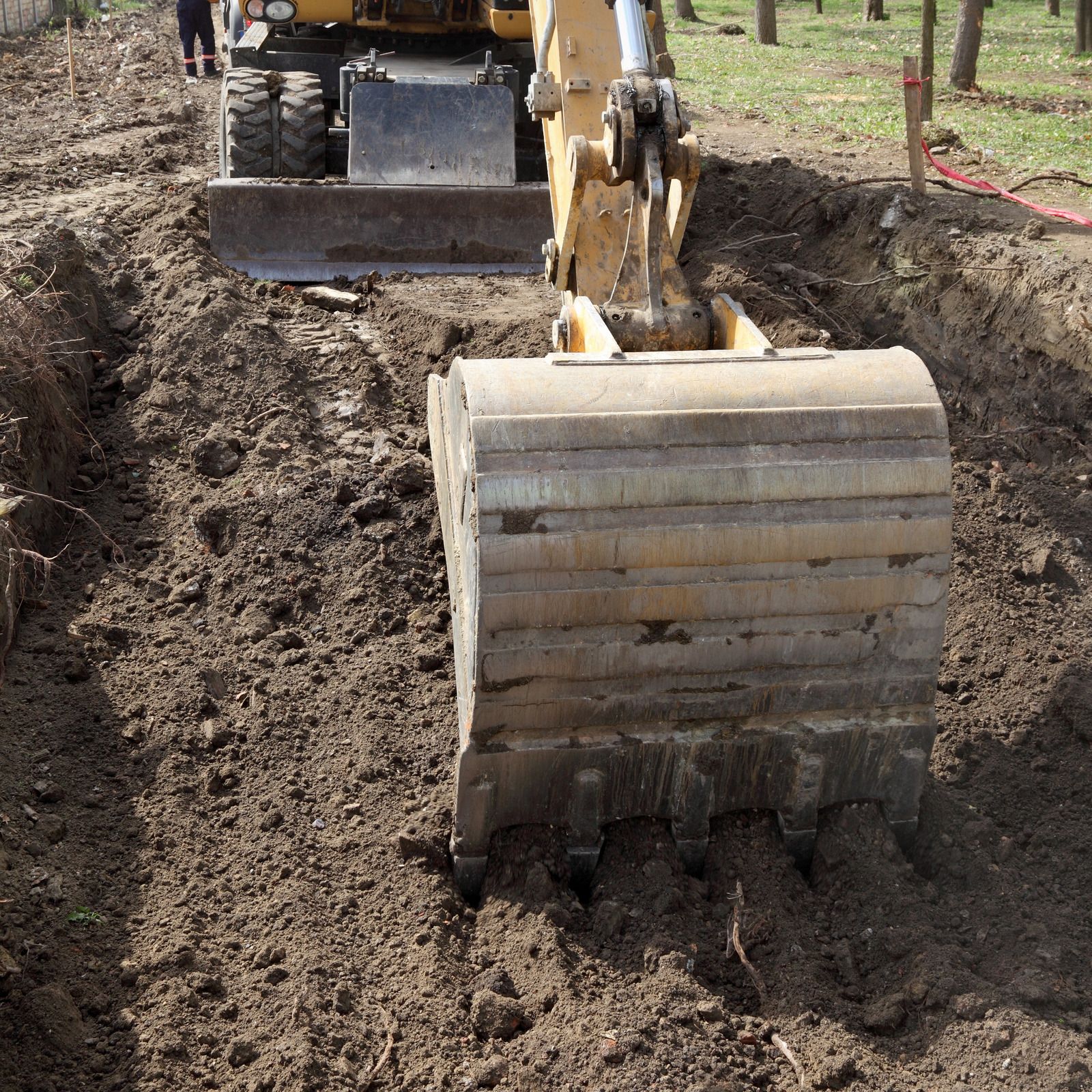 White bathtub with tiled walls in a bathroom, light brown floor, faucet on the side.