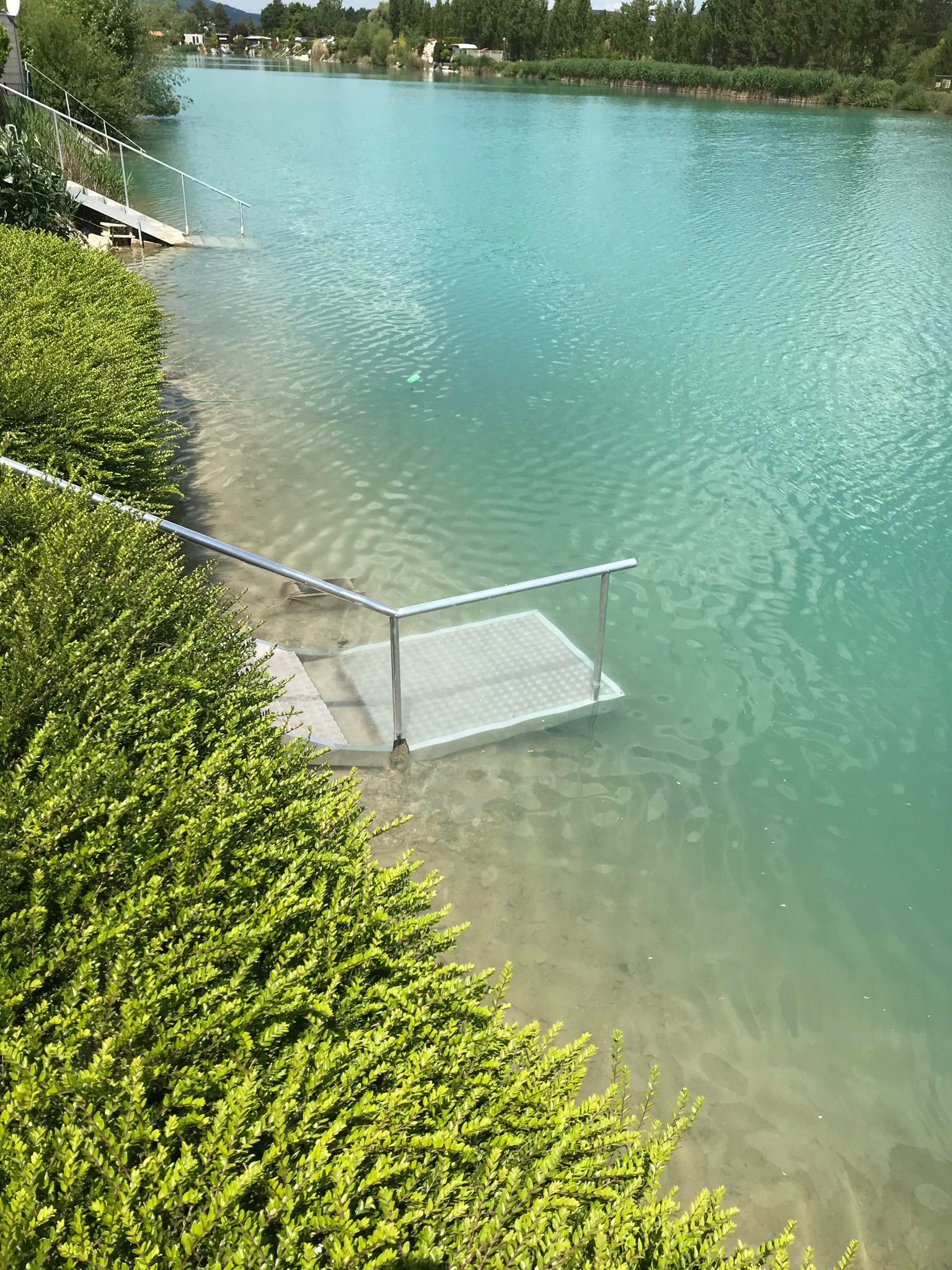 Eine Treppe führt zu einem See mit einem Steg im Wasser.