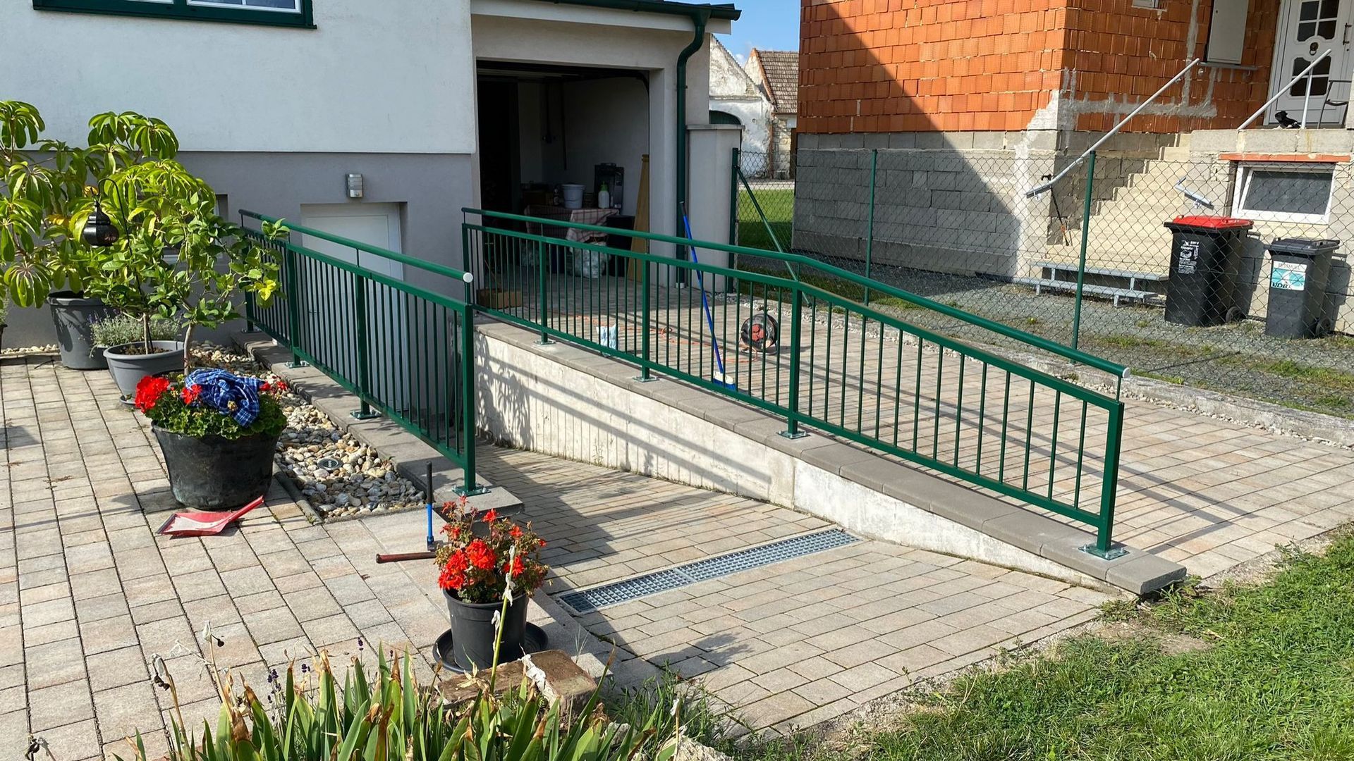 Eine Rampe mit einem grünen Geländer führt zu einem Haus.
