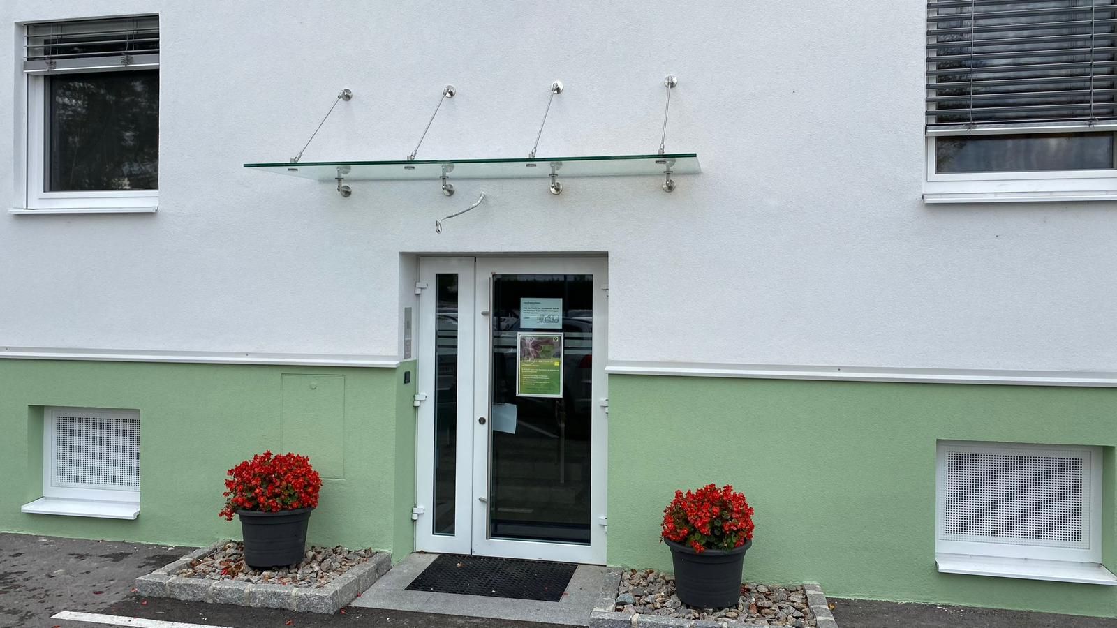 Ein grün-weißes Gebäude mit einem Glasdach über der Tür