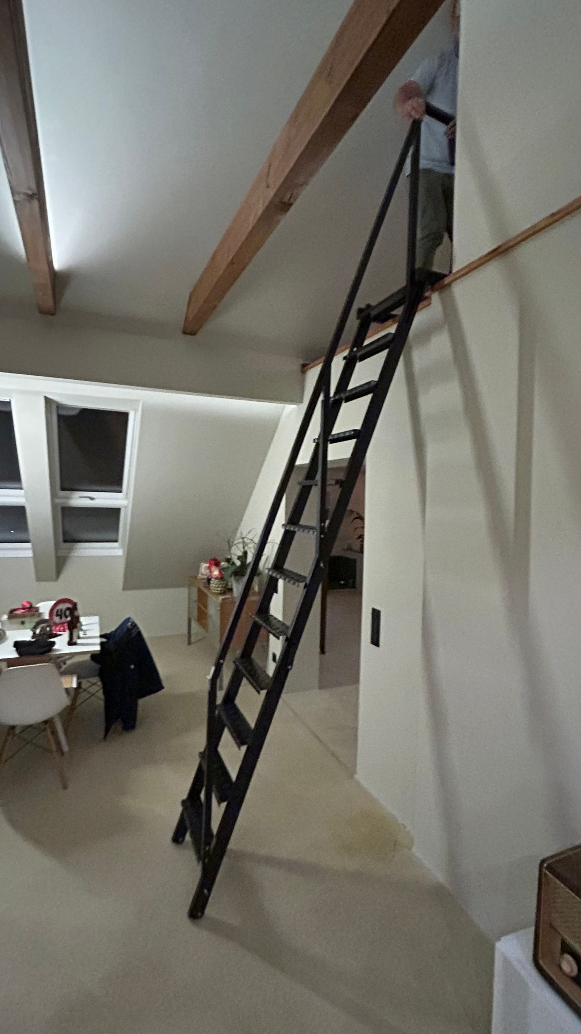 Schwarze Leiter führt zu einer Öffnung in einer Wand im Innenbereich. Person oben.