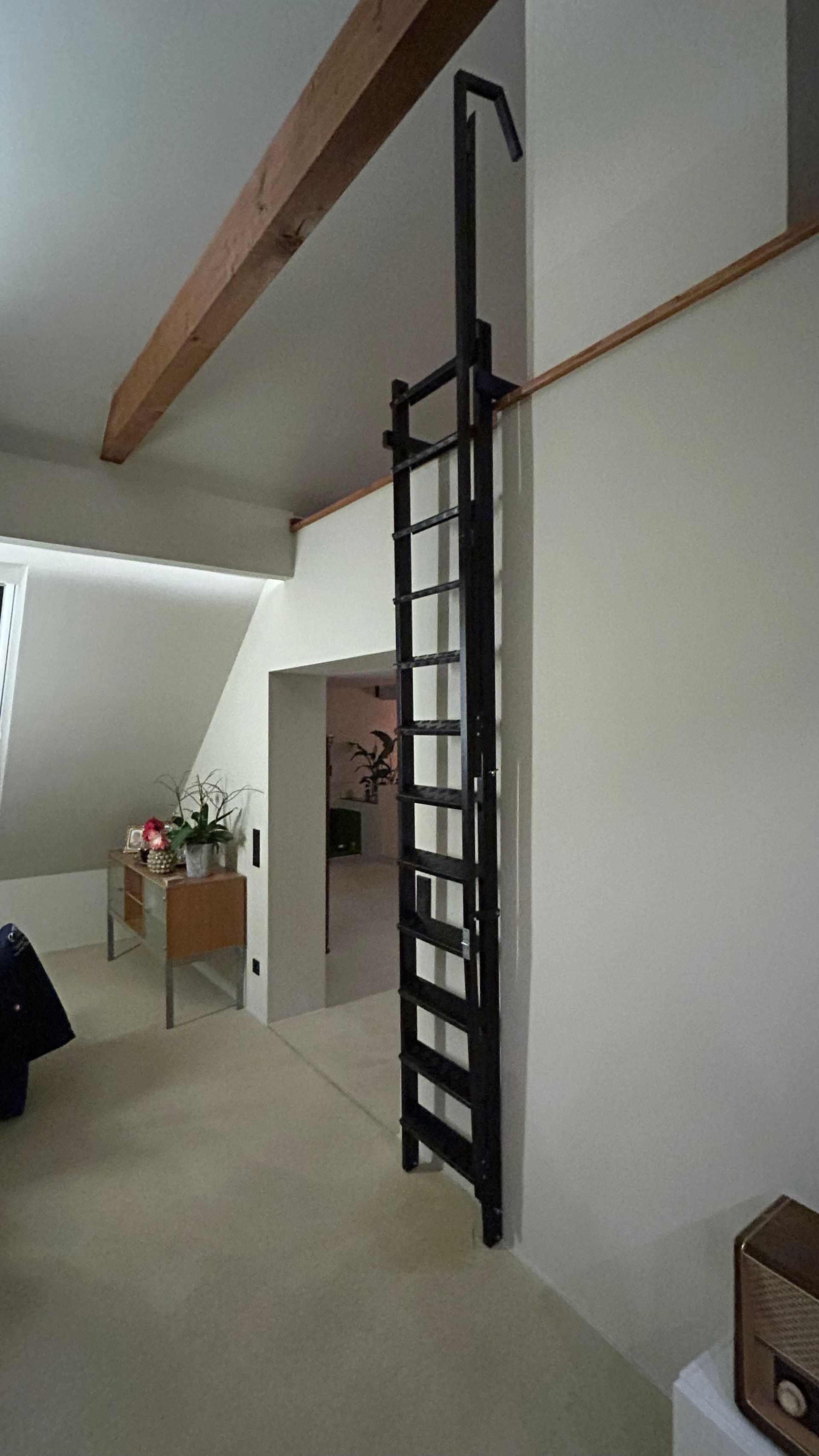 Eine schwarze Metallleiter ist an einer weißen Wand befestigt.