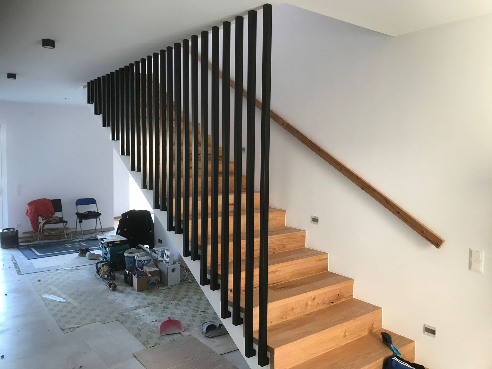 Eine Holztreppe mit schwarzem Geländer und Holzhandlauf