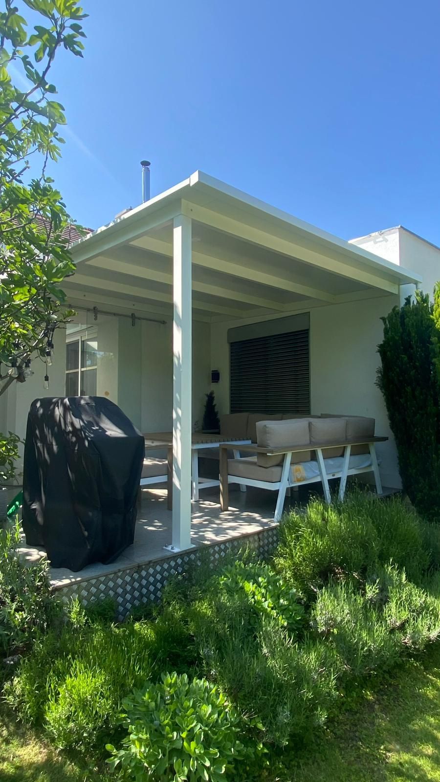 Ein weißes Haus mit einer überdachten Terrasse im Hinterhof.