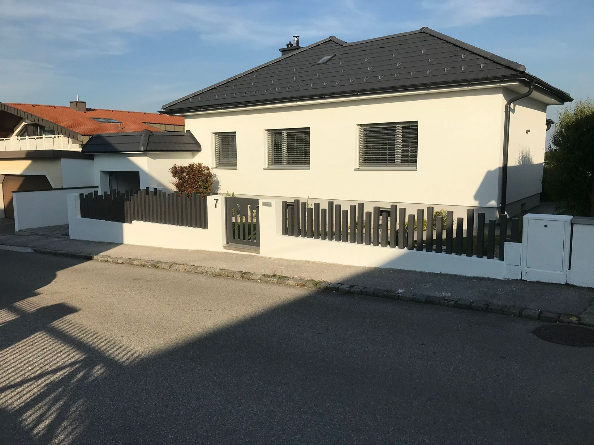 Ein weißes Haus mit einem schwarzen Zaun davor