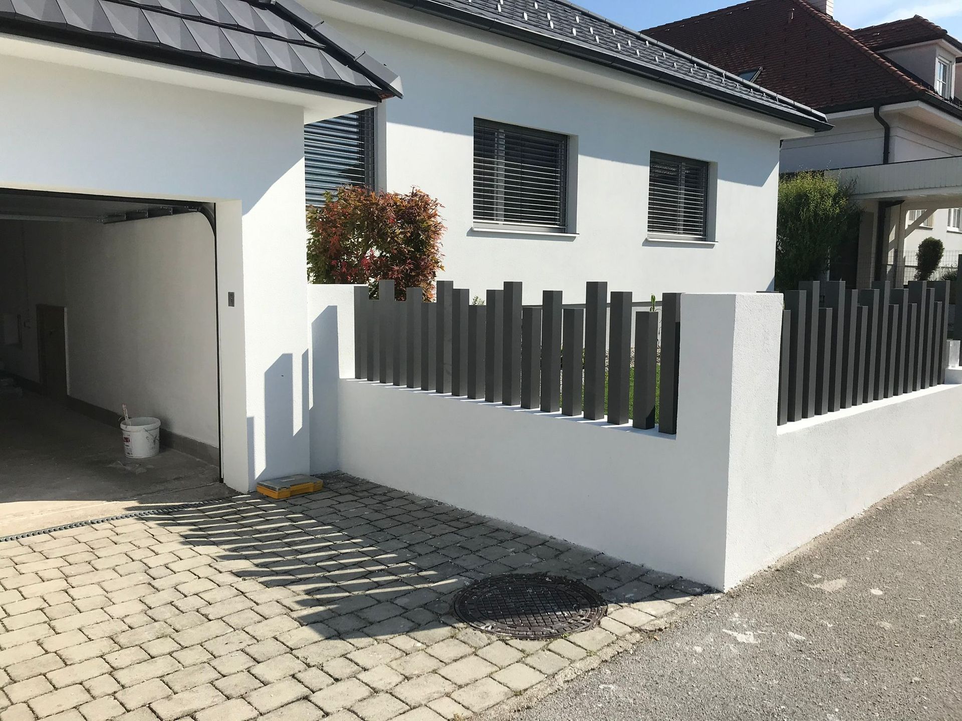 Ein weißes Haus mit einem schwarzen Zaun aus Metall und einer Garage