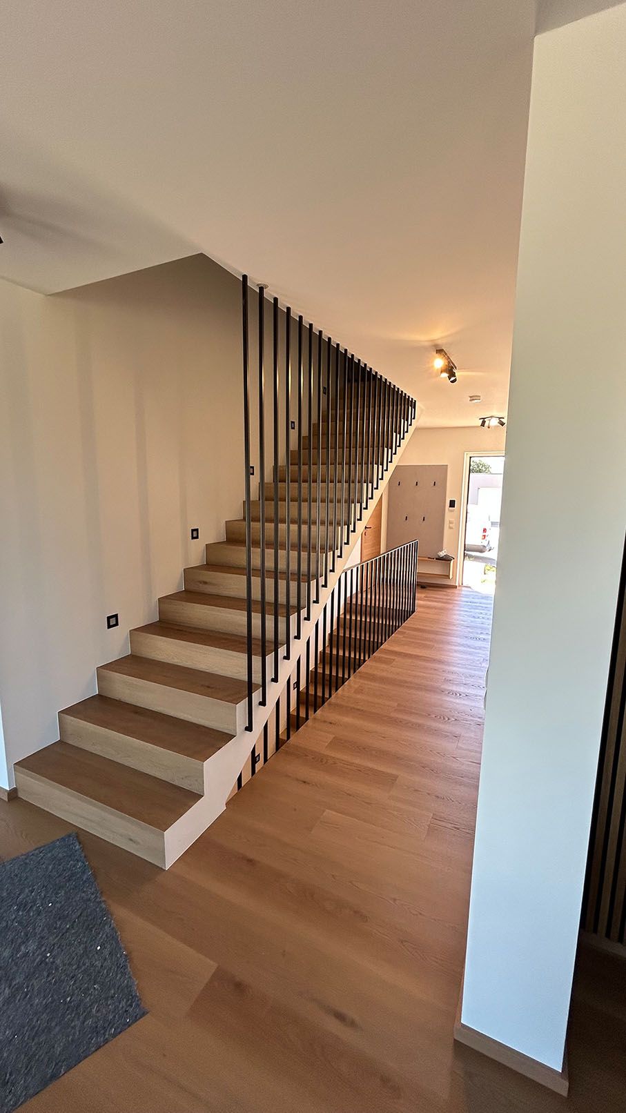 Eine Holztreppe mit schwarzem Geländer und Holzhandlauf