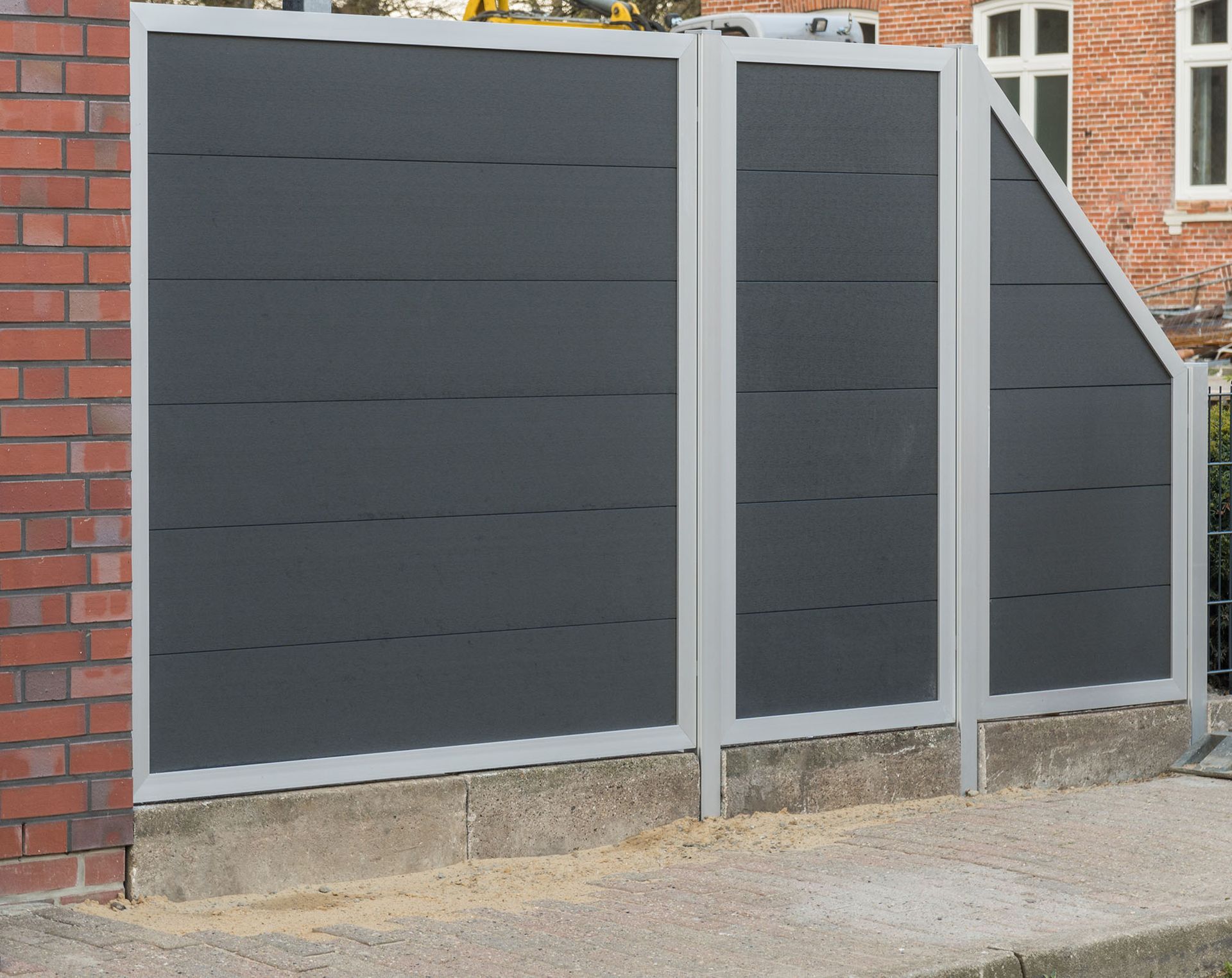 Eine Backsteinmauer mit einem Sichtschutzzaun aus Metall davor