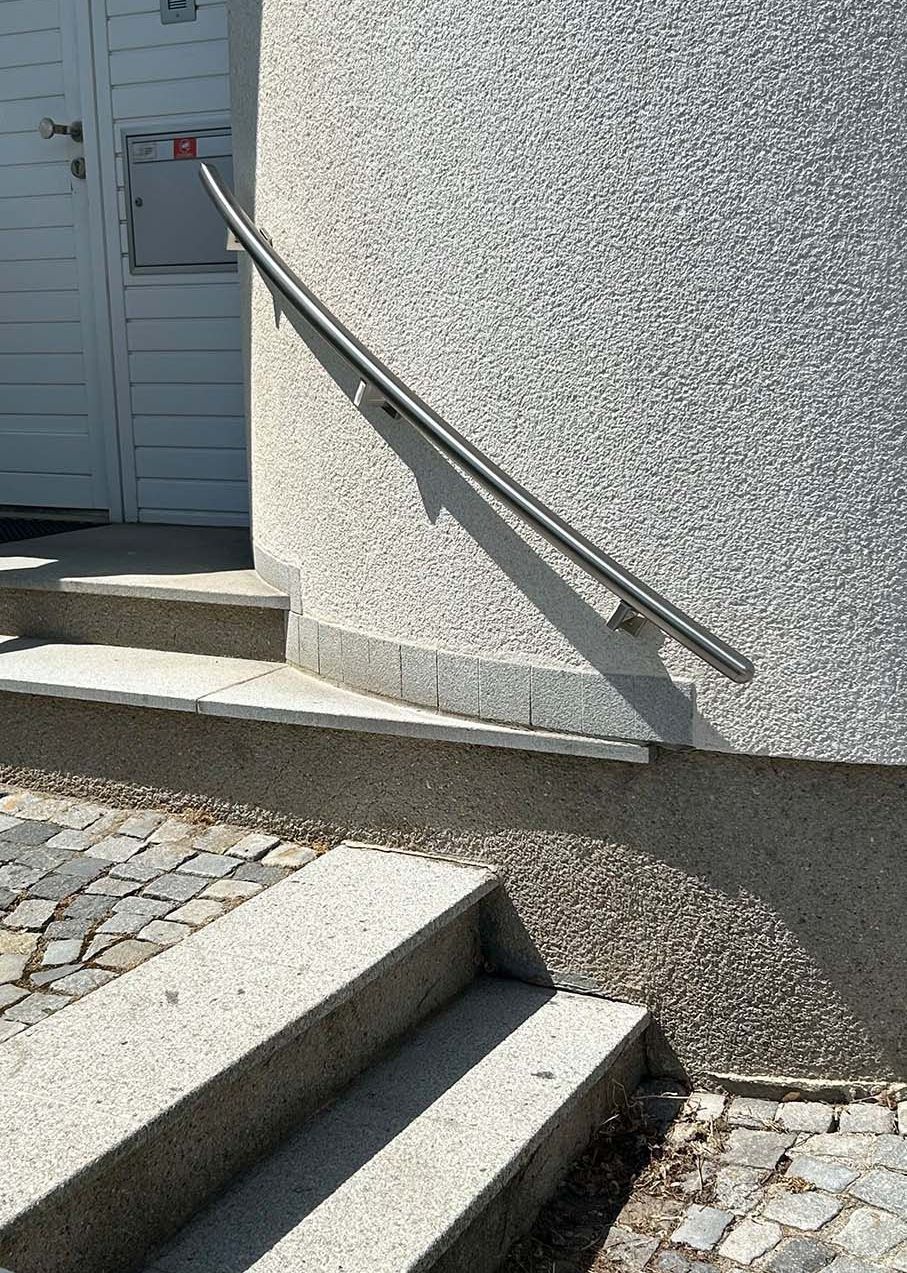 Eine Treppe mit schwarzem Geländer und einer Pflanze im Hintergrund.