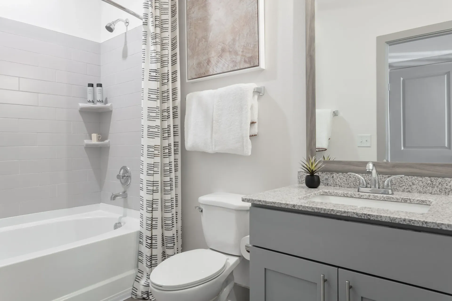 Bathroom featuring a tub/shower combo, white subway tiles, a curtain, towel rack, and a gray granite countertop vanity.