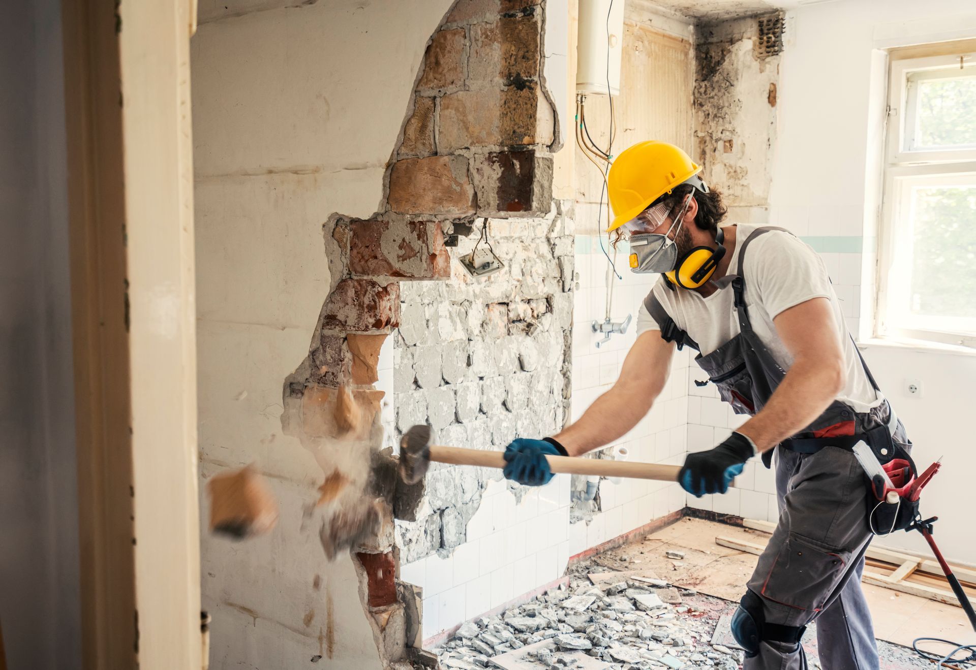 Worker Using Hammer for a Demolition service and Wearing Safety Equipment