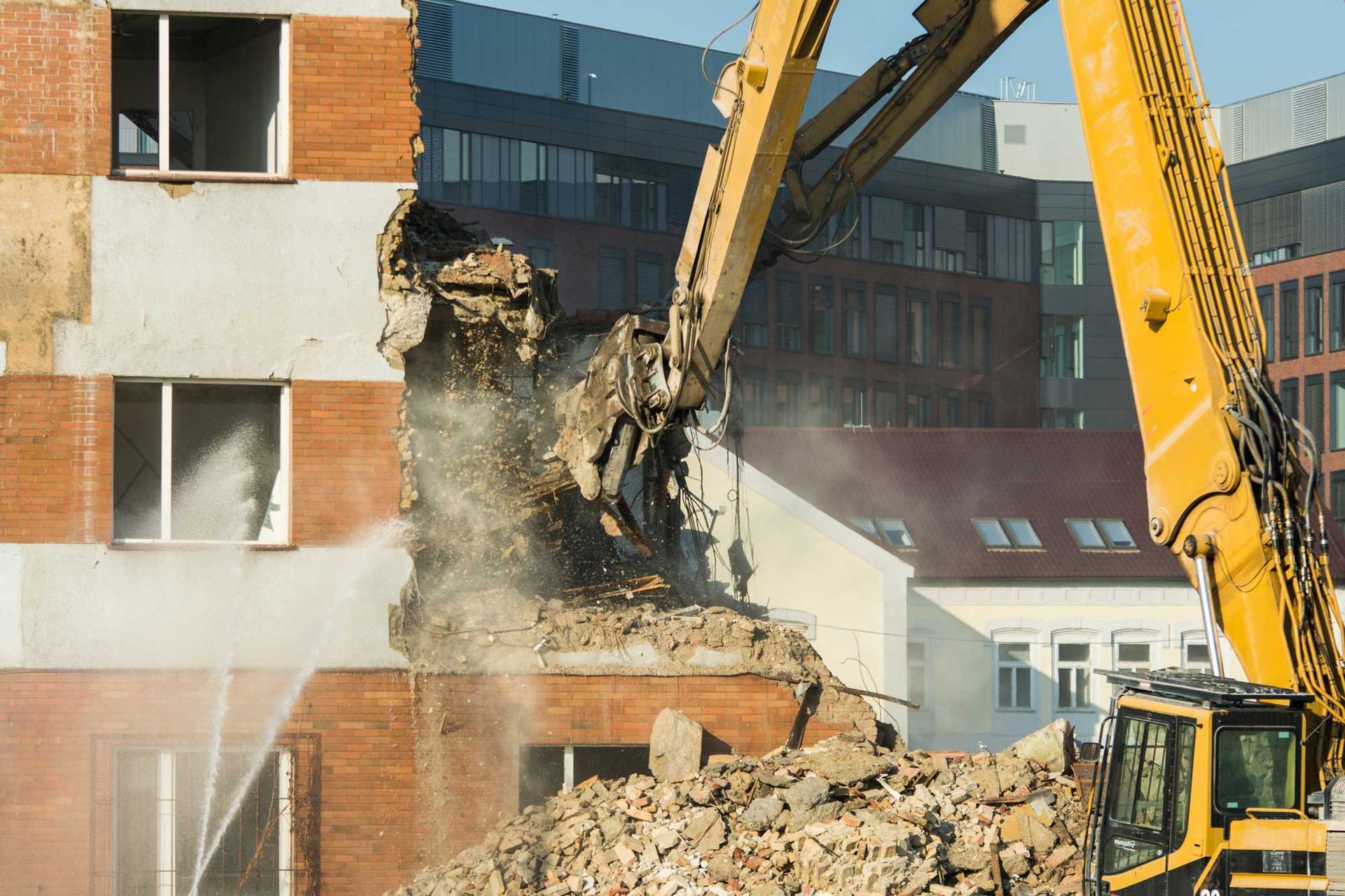 Yellow excavator demolishes concrete structure amid urban backdrop. Yellow excavator demolishes concrete structure amid urban backdrop.
