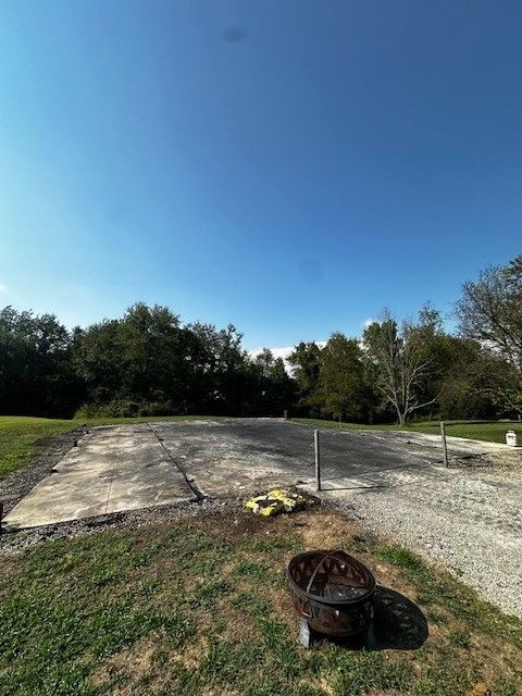 A fire pit is sitting in the middle of a grassy field.