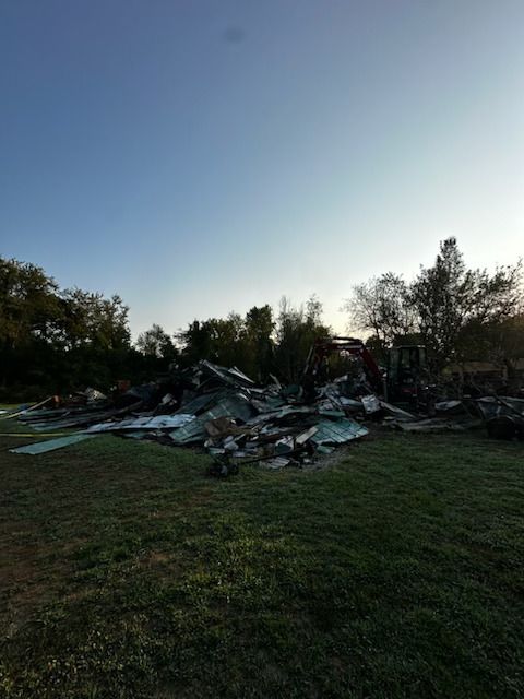 A large pile of junk is sitting in the middle of a grassy field.
