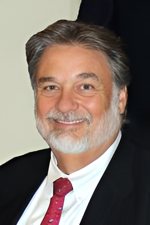 A man in a grey shirt is smiling for the camera